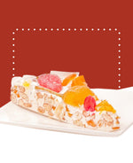 Gâteau nougat blanc avec fruits confits, découpé en parts, sur un plat blanc.
