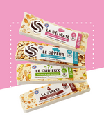 Assortiment de quatre barres de nougat avec différentes saveurs et textures.